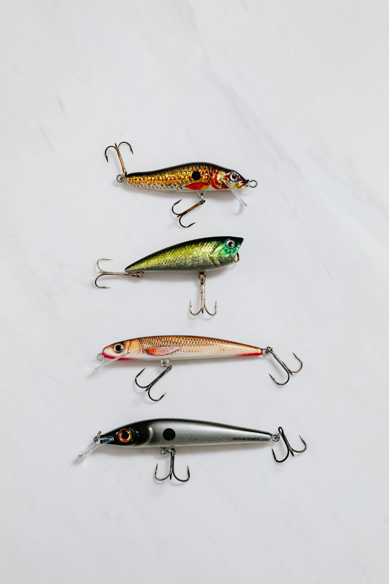 Flat lay of four vibrant fishing lures on a light background, displaying varied designs.
