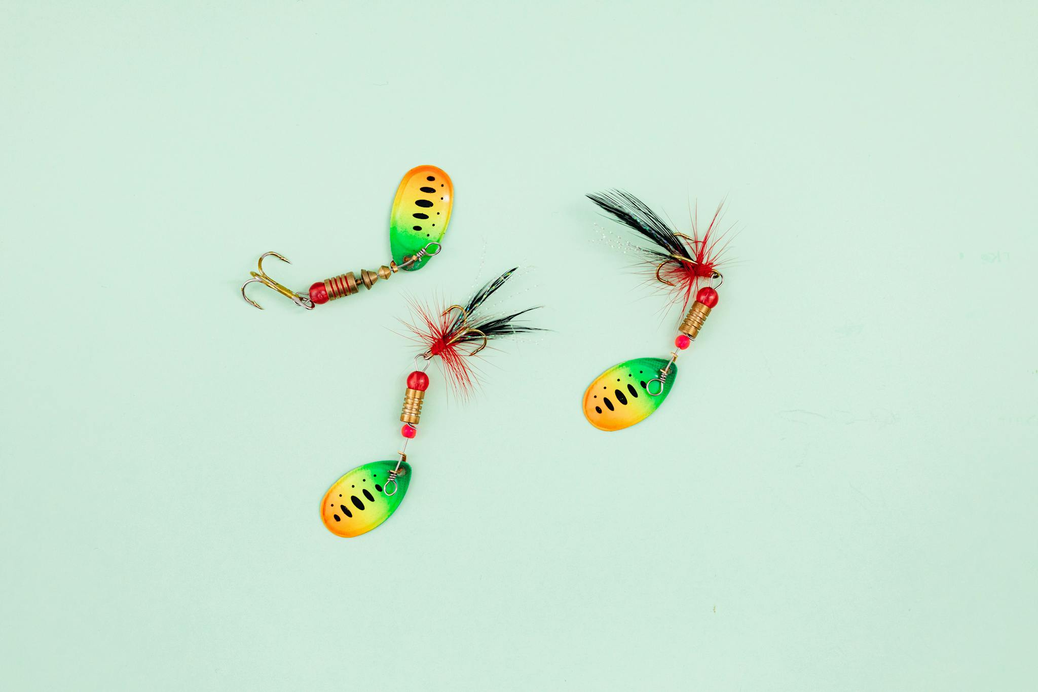 Vibrant fishing lures arranged on a pale green surface, ideal for anglers.